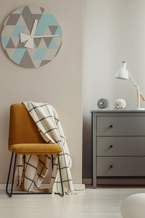 Stilfull gul stol i elegant inre med den gråa träbyrån fotografering för bildbyråer