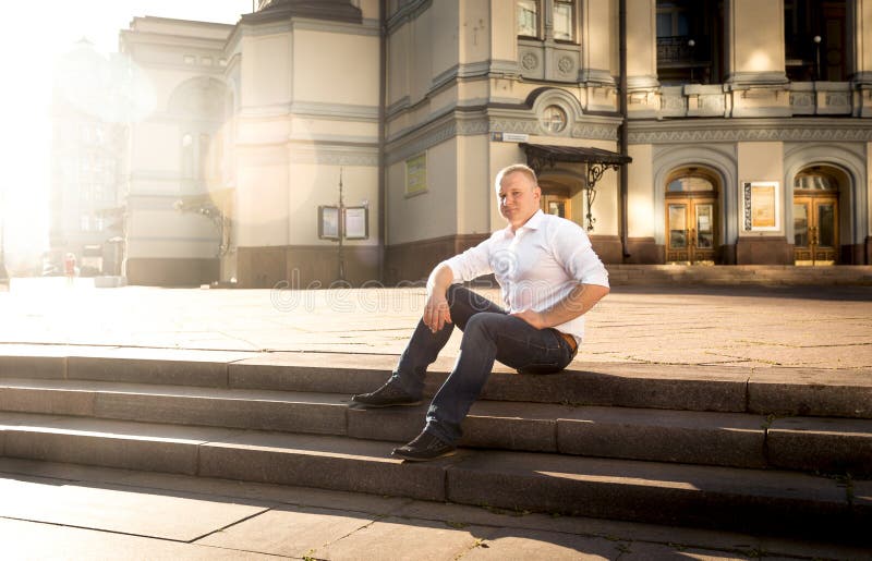 Stilfull man som kopplar av på stentrappa på stor klassisk byggnad royaltyfri bild Stilfull man som kopplar av på stentrappa på stor klassisk byggnad royaltyfri bild