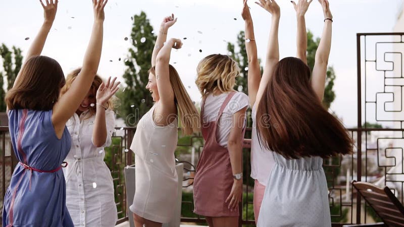 Stilfulla flickor på ungmö festar utanför på terrassen Kasta silverkonfettier in i luften Den lyckliga livsstilen, tycker om