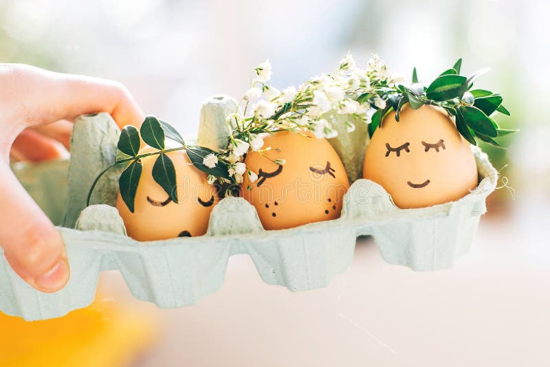 Stilfulla påskägg med gulliga framsidor i blom- kranskronor i lådamagasin Moderna söta easter ägg med blommor och sömniga ögon royaltyfria bilder Stilfulla påskägg med gulliga framsidor i blom- kranskronor i lådamagasin Moderna söta easter ägg med blommor och sömniga ögon royaltyfria bilder