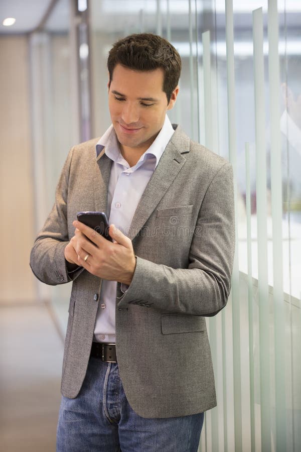 Stilig affärsman på kontoret på telefonen, sms, mejl arkivbilder Stilig affärsman på kontoret på telefonen, sms, mejl arkivbilder