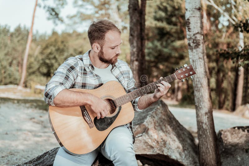 Stilig blondin-haired skäggig inspirerad mankänsla, medan spela gitarren arkivbilder Stilig blondin-haired skäggig inspirerad mankänsla, medan spela gitarren arkivbilder