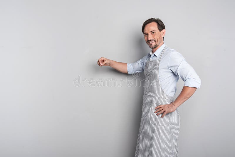 Stilig glad ung man som gör en gest i ett förkläde fotografering för bildbyråer Stilig glad ung man som gör en gest i ett förkläde fotografering för bildbyråer