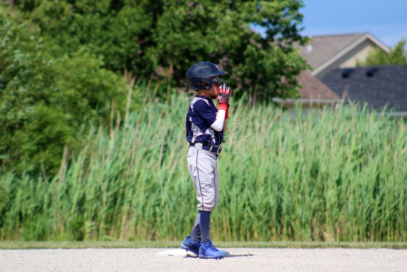 Stilig gullig ung pojke som spelar baseball som väntar och skyddar grunden arkivbild Stilig gullig ung pojke som spelar baseball som väntar och skyddar grunden arkivbild