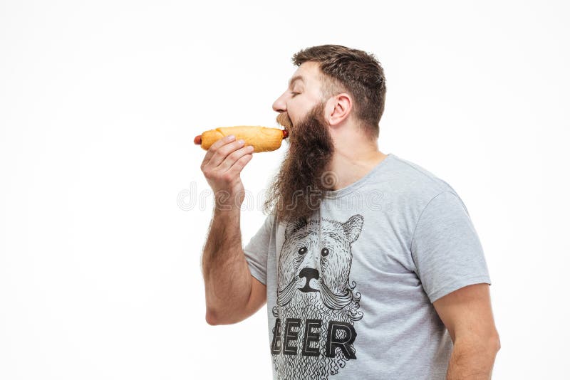 Stilig man med skägganseende och ätavarmkorven arkivfoto Stilig man med skägganseende och ätavarmkorven arkivfoto