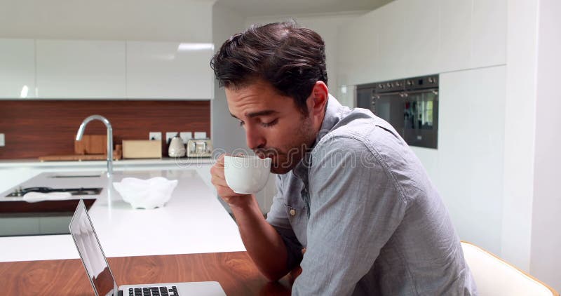 Stilig man som dricker kaffe och använder bärbara datorn lager videofilmer