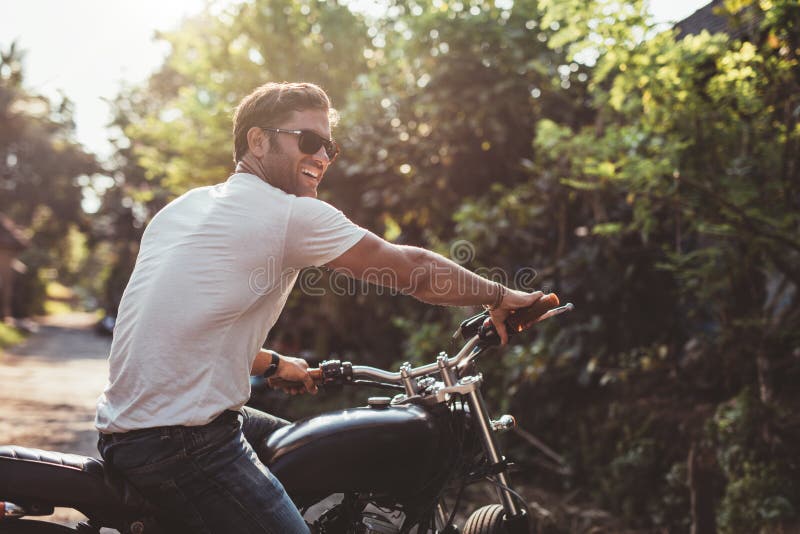 Portrait of handsome young man on motorcycle. Happy caucasian male on motorbike looking away and smiling. Portrait of handsome young man on motorcycle. Happy caucasian male on motorbike looking away and smiling.