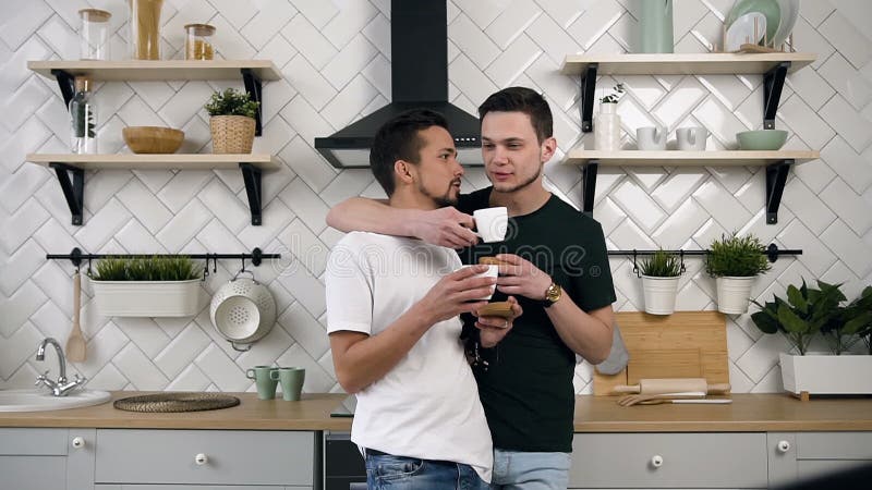Stiliga glade par är krama och dricka kaffe Glat f? rh? llandebegrepp Unga manliga glade par som kramar sig stock video