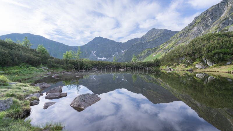 Still alpine tarn reflecting surrounding mountains and environment, Slovakia, Europe