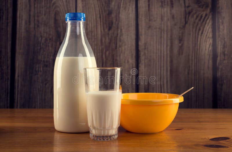 Still life of bottle of milk, glass of milk and yellow plastic bowl