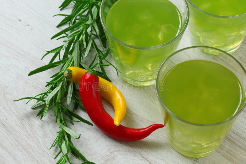 Still life with bright green cocktails on wooden background, chilli pepper and rosemary near