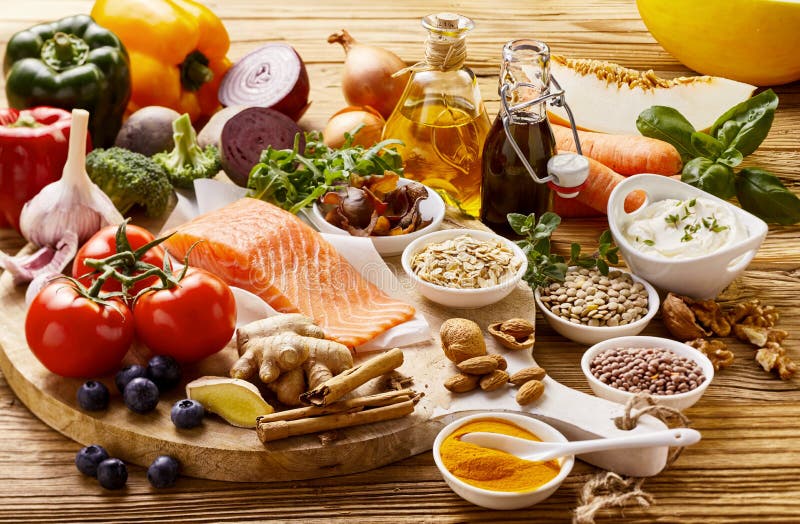 Still life concept of healthy heart and cardiovascular foods with raw salmon, spices, lentils, herbs, blueberries, broccoli, garlic, tomato, nuts, soy sauce, carrots and olive oil on a rustic table. Still life concept of healthy heart and cardiovascular foods with raw salmon, spices, lentils, herbs, blueberries, broccoli, garlic, tomato, nuts, soy sauce, carrots and olive oil on a rustic table