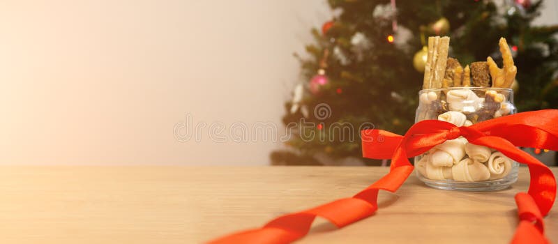 Still life of dog food and healthy treats with red ribbon on christmas tree background with copy space. christmas gift