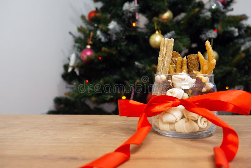 Still life of dog food and healthy treats with red ribbon on christmas tree background with copy space. christmas gift