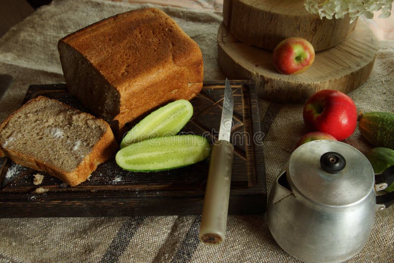 Still life with fresh bread and salt, next to a green cucumber from the garden, rustic style royalty free stock photography Still life with fresh bread and salt, next to a green cucumber from the garden, rustic style royalty free stock photography