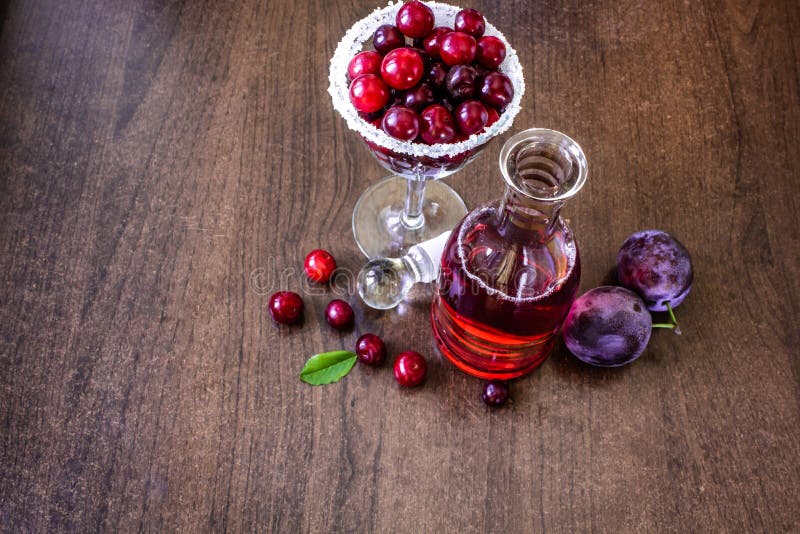 still life of fruit and wine. Cherry wine in the carafe, in a glass of cherries, on a wooden table cherry and plum stock images still life of fruit and wine. Cherry wine in the carafe, in a glass of cherries, on a wooden table cherry and plum stock images