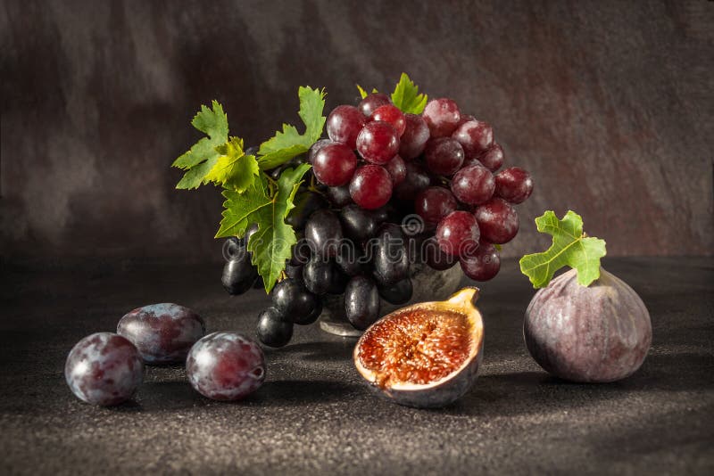 Still life with fruits: grape, fig, plum in the antique copper tin cup