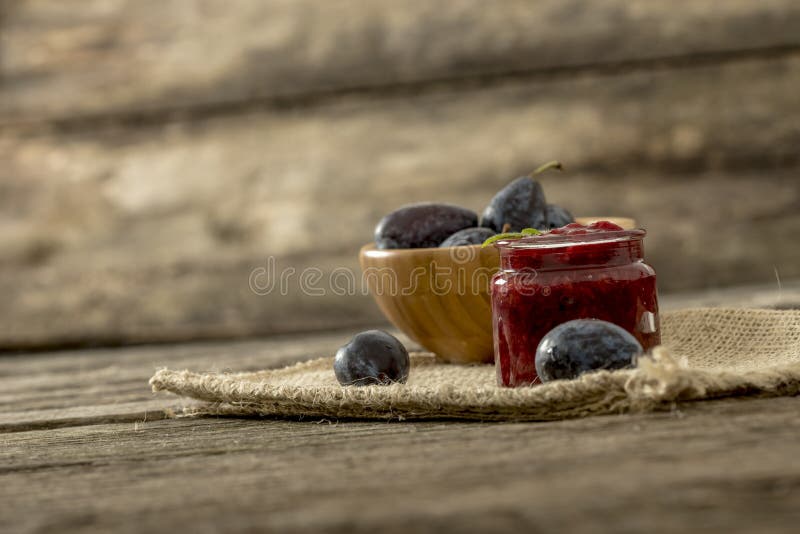 Still life with a jar of home made plum marmelade and wooden bow