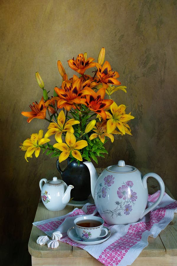 A teacup, teapots and a bouquet of beautiful lilies .