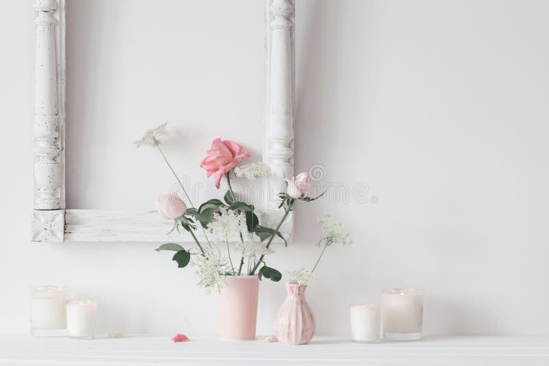 Still life with pink roses and candles on white background