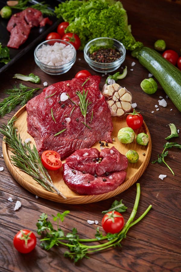 Still Life of Raw Beef Meat with Vegetables on Wooden Plate Over White ...