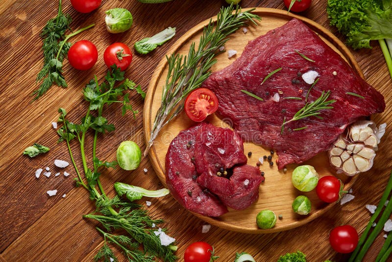 Still Life of Raw Beef Meat with Vegetables on Wooden Plate Over White ...