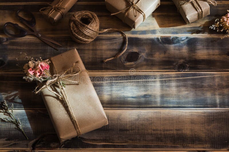 Still life shot of Beautiful small handmade DIY gift box package with flowers and decorative rope on wood background. Vintage stock photography Still life shot of Beautiful small handmade DIY gift box package with flowers and decorative rope on wood background. Vintage stock photography