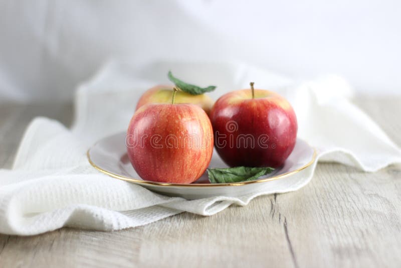 Still life with red apples and leaves on table