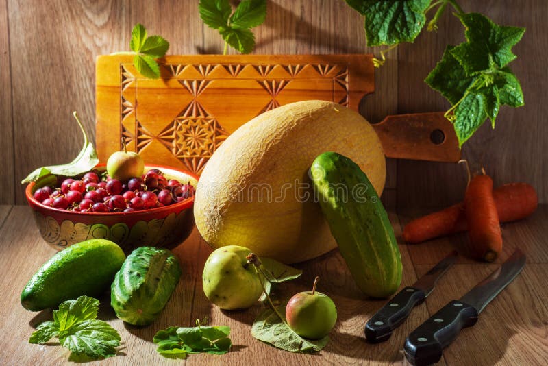 Still life with vegetables and berries. autumn still life with melon cucumbers carrots and gooseberries knives and spoons.