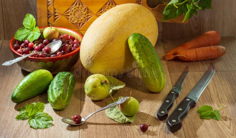 Still life with vegetables and berries. autumn still life with melon cucumbers carrots and gooseberries knives and spoons.