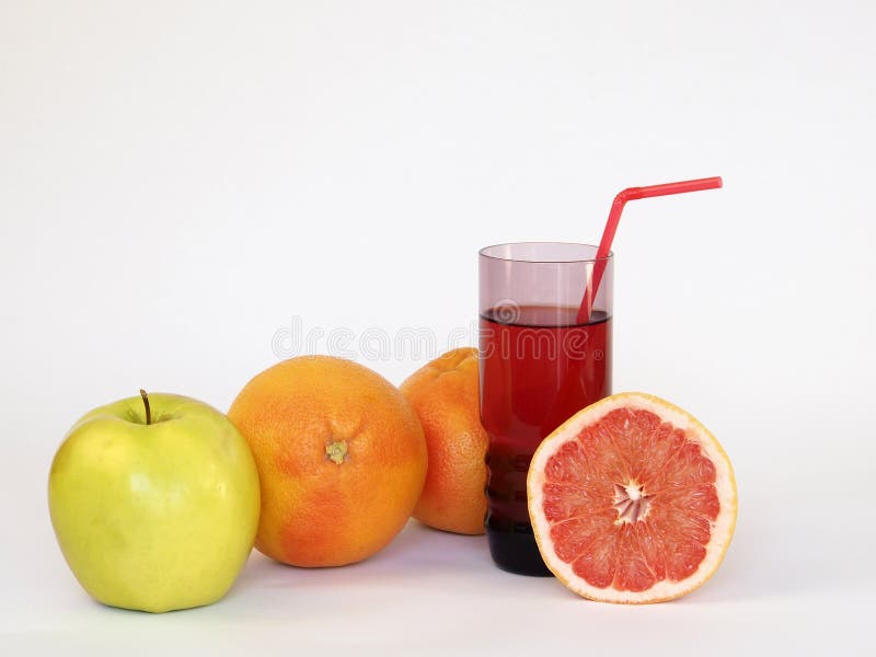 Still life. On the White background are: an apple, two whole grapefruits and a glass of juice, from which sticks out a tube for co royalty free stock photo Still life. On the White background are: an apple, two whole grapefruits and a glass of juice, from which sticks out a tube for co royalty free stock photo
