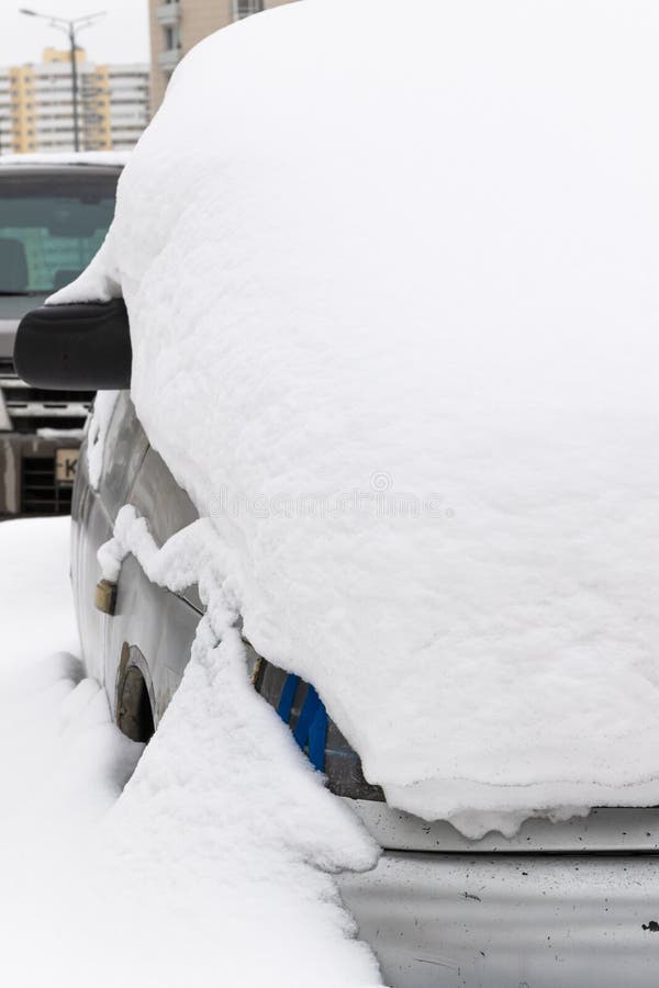 Stillgelegtes, kaputtes Auto, das an einem kalten Wintertag unter einer großen Schneeschicht auf der Straße geparkt wird. Alter verlassener, kaputter Wagen, der an einem kalten Wintertag unter einer großen Schneeschicht auf der Straße geparkt wurde
