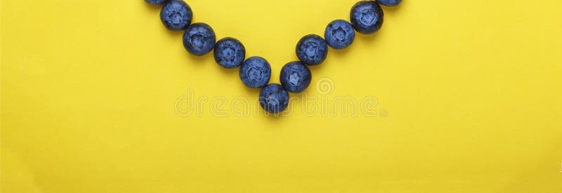 Stilminimalism Blåbär i formen av hjärta på en gul bakgrund Begreppet: blåbär förhindrar hjärtsjukdomen