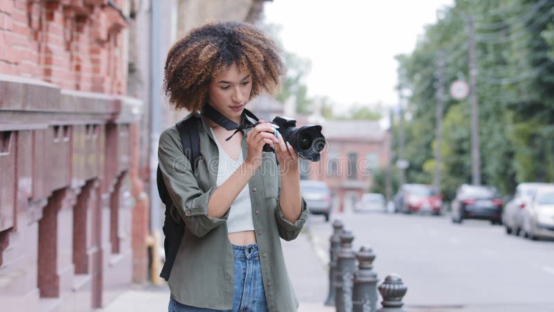 Stilvoll attraktiv lockig afrikanisch amerikanisch schwarz Frau zu Fuß Straße und Erkundung Sightseeing mit Kamera. junge Frau