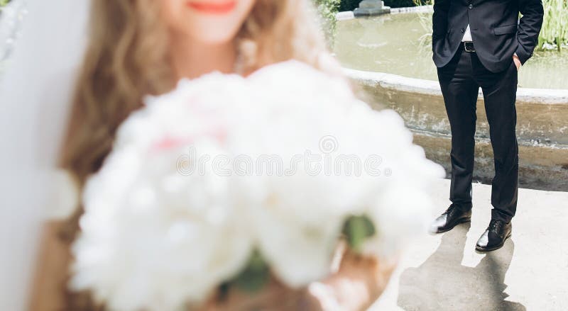 Stilvolle Braut mit Pfingstrosenblumenstrauß und Bräutigam in der Klage, die in der Sonne aufwirft lizenzfreie stockfotos Stilvolle Braut mit Pfingstrosenblumenstrauß und Bräutigam in der Klage, die in der Sonne aufwirft lizenzfreie stockfotos