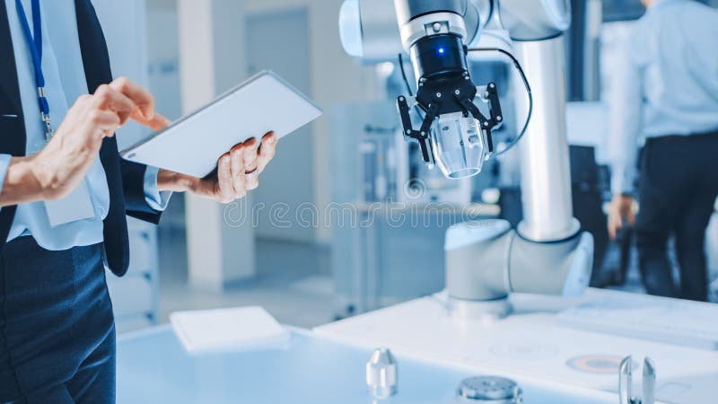 Stilvolle Roboteringenieurin der Industrie verwendet Tablet-Computer, um Roboter zu programmieren und zu manipulieren. Stilvolle Roboteringenieurin der Industrie verwendet Tablet-Computer, um Roboterarm zum Heben bewegter Objekte zu programmieren und zu manipulieren. Technologieforschungseinrichtung für maschinelles Lernen und Cloud Computing