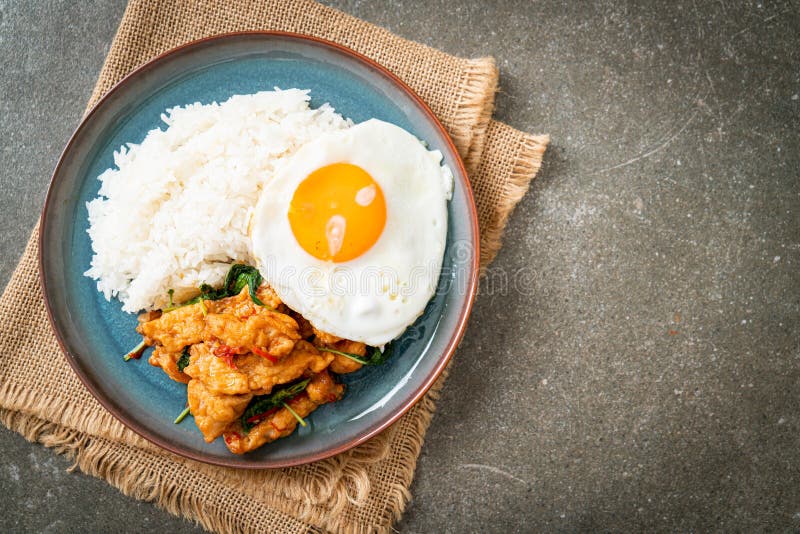 Stirfried Fried Fish with Basil and Fried Egg Topped on Rice Stock