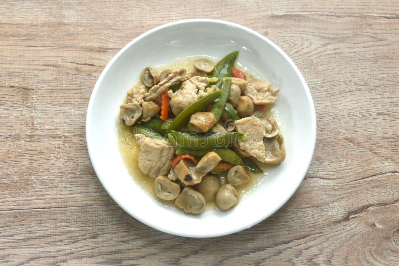 Stir fried green pea and straw mushroom with pork in soybean sauce on plate royalty free stock photography
