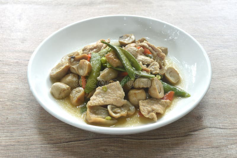 Stir fried green pea and straw mushroom with pork in soybean sauce on plate stock photo