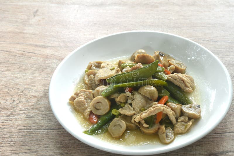Stir fried green pea and straw mushroom with pork in soybean sauce on plate stock photos