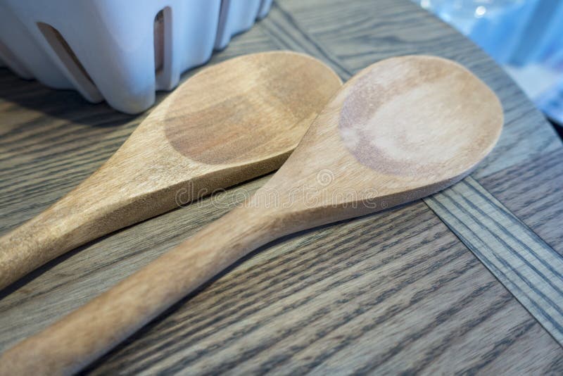 2 light tan wooded spoons on a wood table. 2 light tan wooded spoons on a wood table