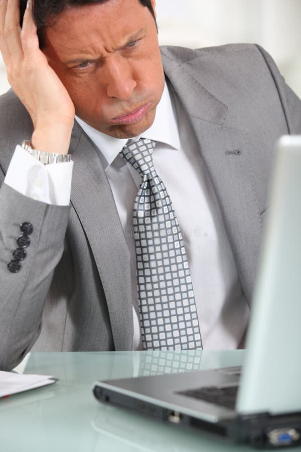 Perplexed man in suit staring at laptop computer. Perplexed man in suit staring at laptop computer