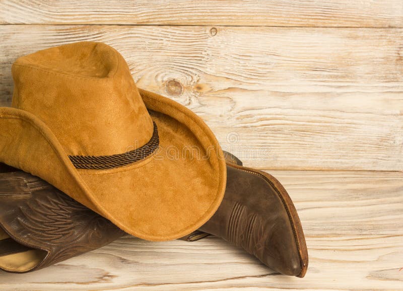 Stivali e cappello di cowboy ad ovest americani sul fondo di legno di struttura fotografie stock Stivali e cappello di cowboy ad ovest americani sul fondo di legno di struttura fotografie stock