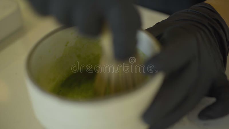 Stolling van barkeiharde handen die matcha green tea in cup mixen. onherkenbare professionele barista die een warme gezondheid voo