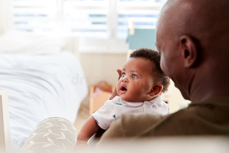 Stolt fader Cuddling Baby Son i barnkammare hemma royaltyfria foton