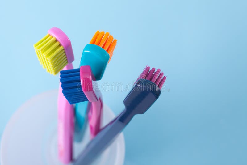 Four toothbrushes - dental hygiene. Top view, selective focused on top of right toothbrush, blue background. Four toothbrushes - dental hygiene. Top view, selective focused on top of right toothbrush, blue background.