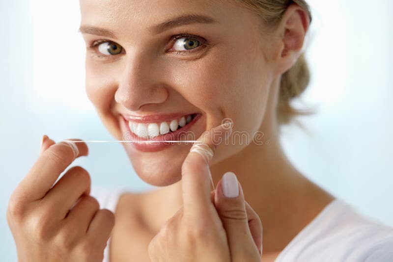 Dental Care. Closeup Portrait Of Beautiful Happy Smiling Young Woman With Perfect Smile Cleaning, Flossing Healthy White Teeth Using Floss. Mouth Hygiene, Oral Health Concept. High Resolution Image. Dental Care. Closeup Portrait Of Beautiful Happy Smiling Young Woman With Perfect Smile Cleaning, Flossing Healthy White Teeth Using Floss. Mouth Hygiene, Oral Health Concept. High Resolution Image