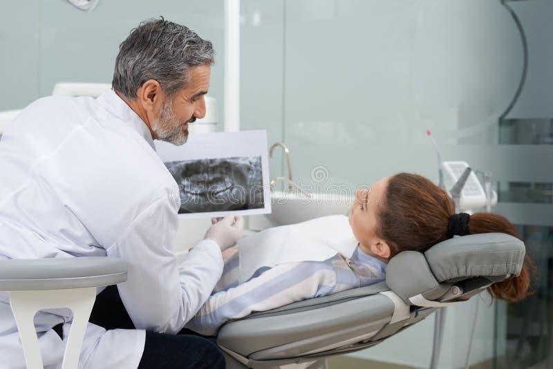 Stomatologist que mostra o raio X dental ao cliente fotografia de stock Stomatologist que mostra o raio X dental ao cliente fotografia de stock