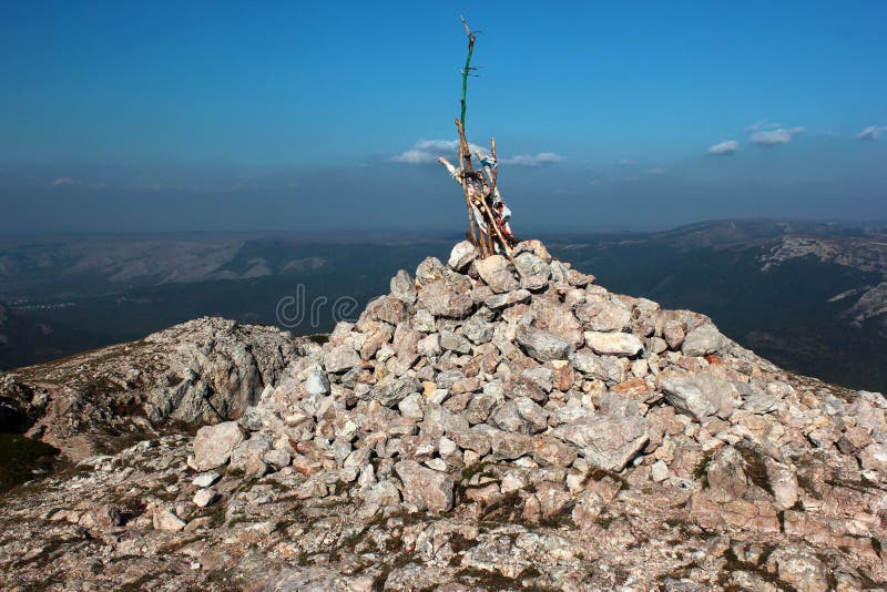 Stone cairn with sticking poles. Pile of rocks on the top of mountain