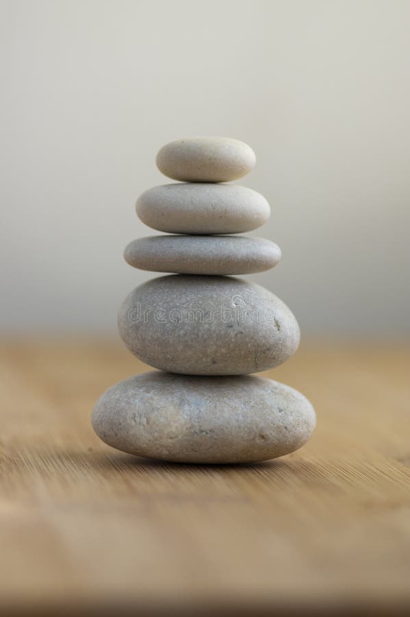 Stone cairn on striped grey white background, five stones tower, simple poise stones, simplicity harmony and balance